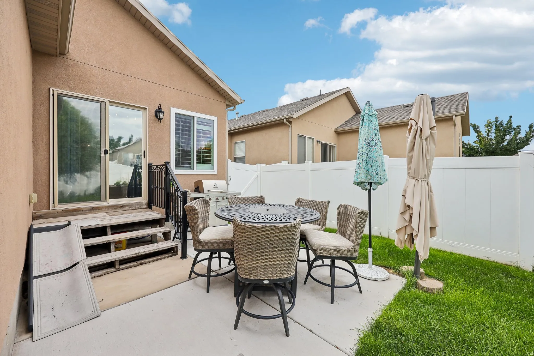 Private patio featuring concrete surfacing, a short staircase with metal railing, and a sliding glass door