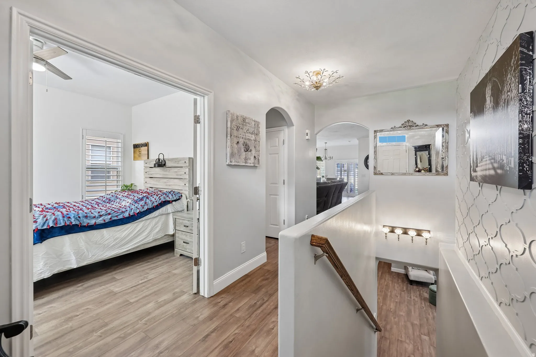 Hallway with wood-finish flooring, an arched entryway, and a decorative wall panel