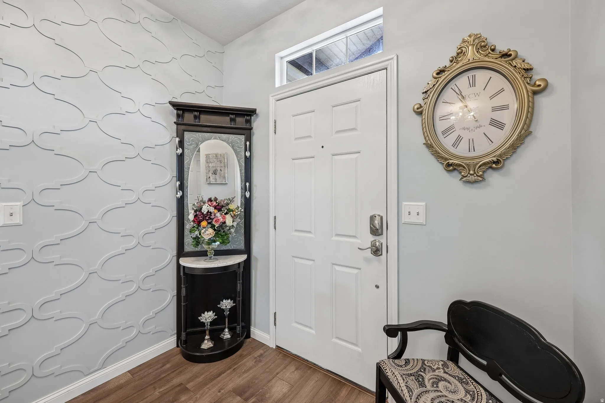Entryway featuring a decorative wall panel, wood-finish flooring, and a transom window above the entry door