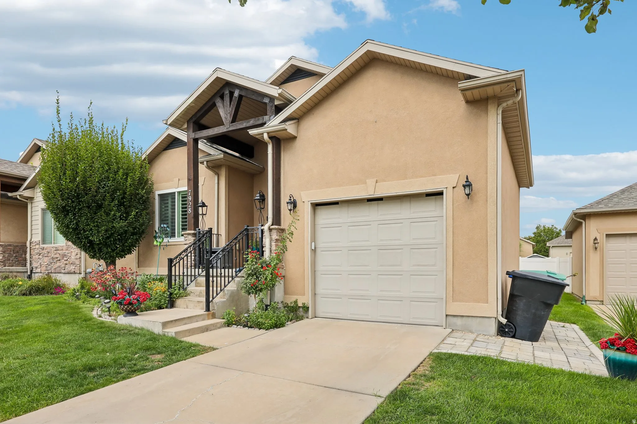 Stucco exterior with a peaked roofline, front-facing garage, and covered entryway with architectural wood beams