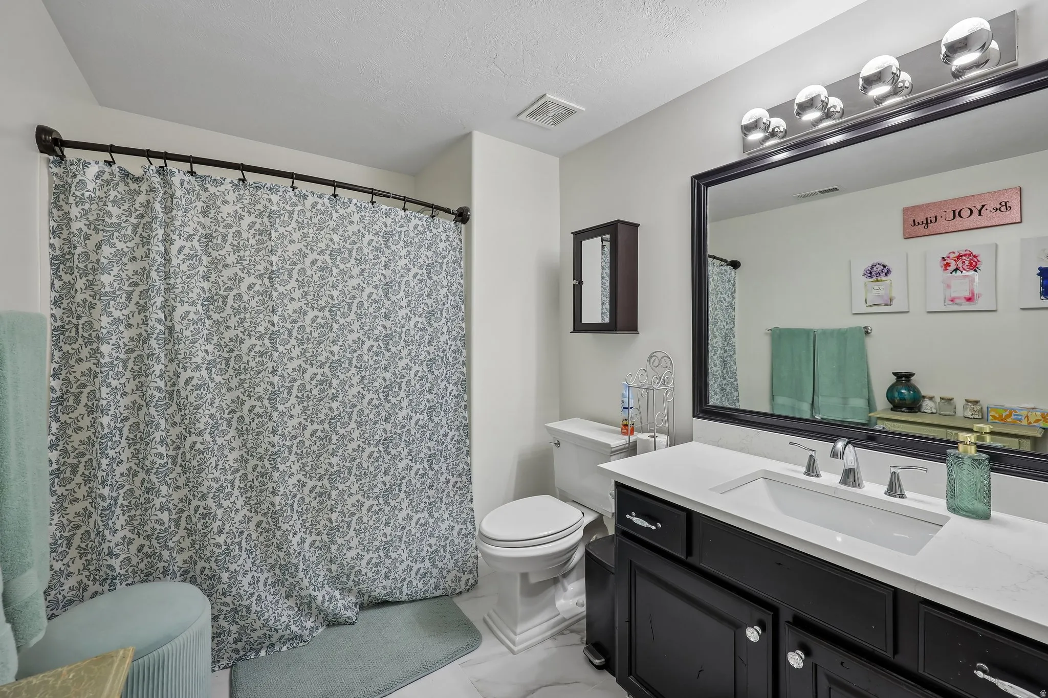 White vanity with a rectangular undermount sink, a chrome two-handle faucet, and black cabinetry