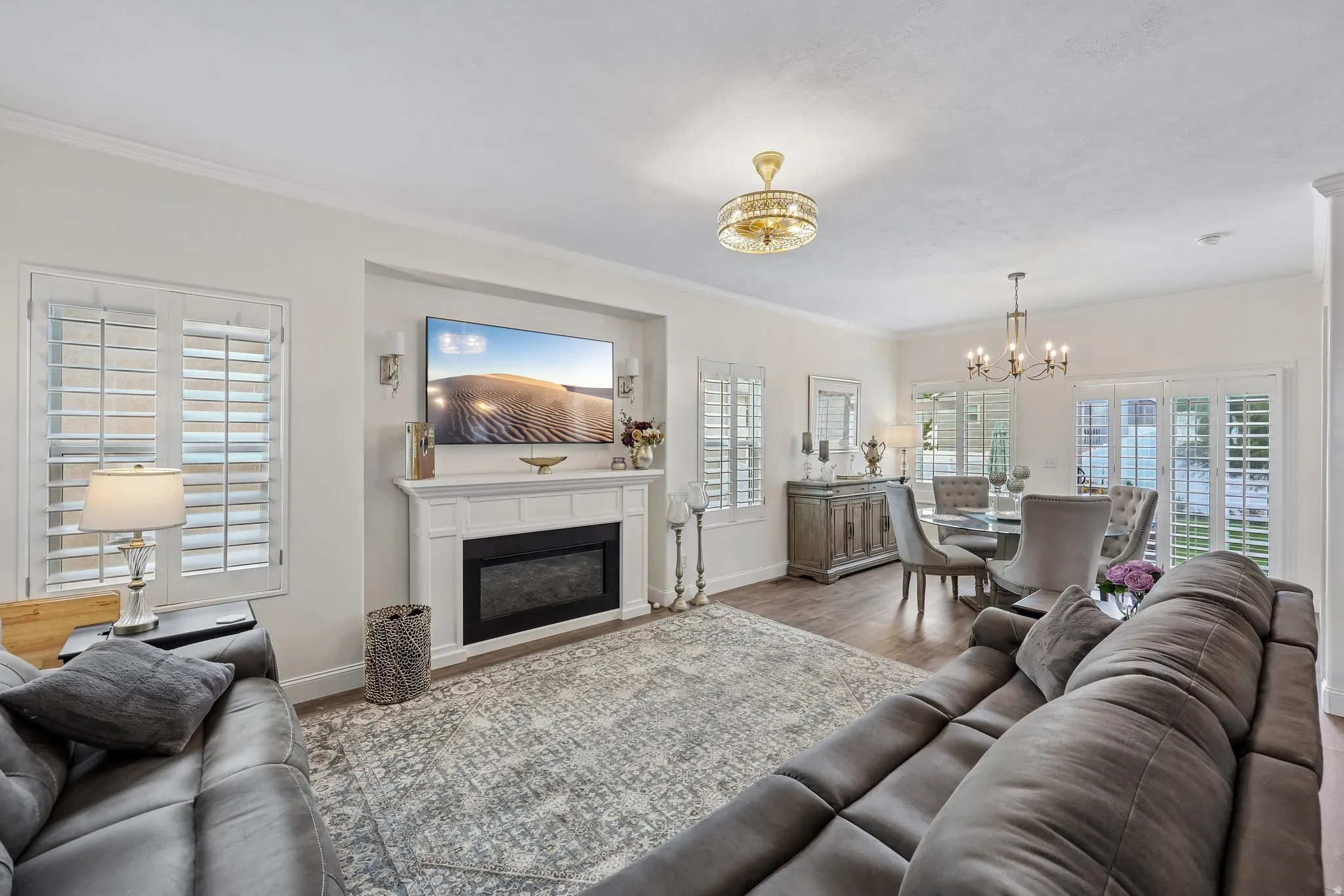 Recessed fireplace with a classic mantel, crown molding, and wood-finish flooring