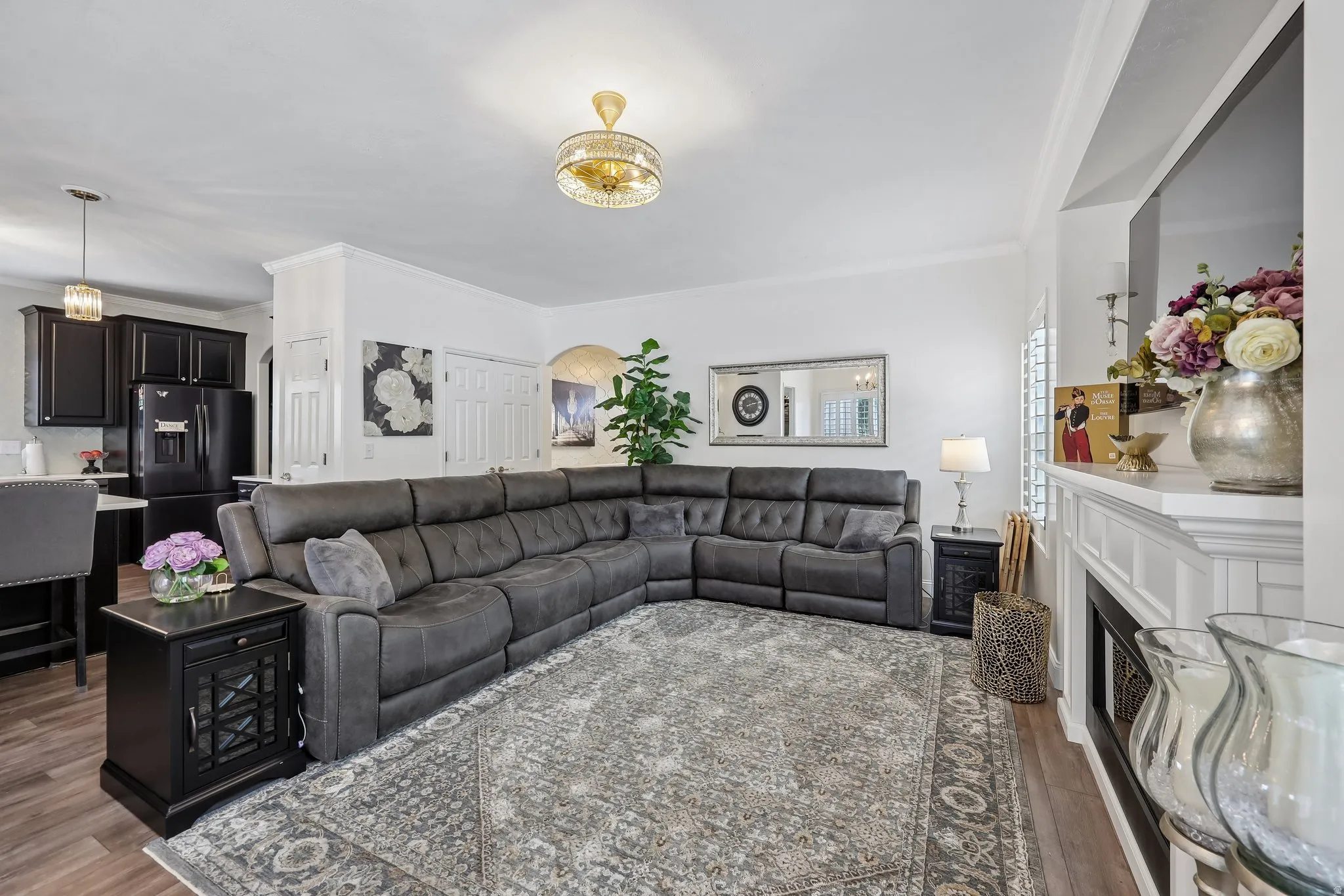 Wood-finish flooring throughout, white crown molding, recessed lighting, and a decorative chandelier