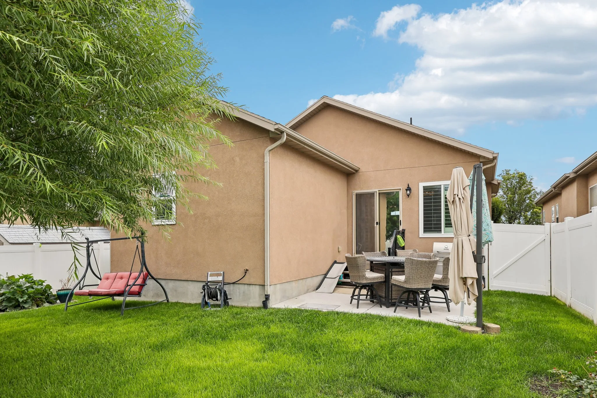 Rear exterior with stucco siding, a concrete patio, sliding glass door, and a grassy yard