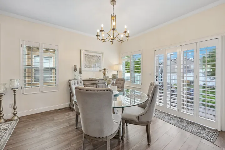 Recessed lighting, crown molding, wood-finish flooring, white plantation shutters, and a glass-paneled patio door