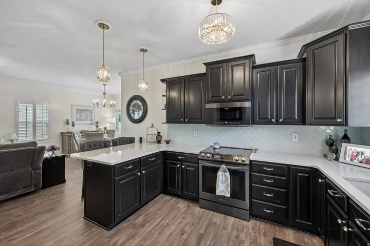Kitchen featuring dark wood-finish cabinetry, white countertops, herringbone tile backsplash, and stainless steel appliances