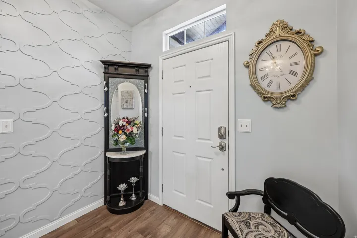 Entryway featuring a decorative wall panel, wood-finish flooring, and a transom window above the entry door