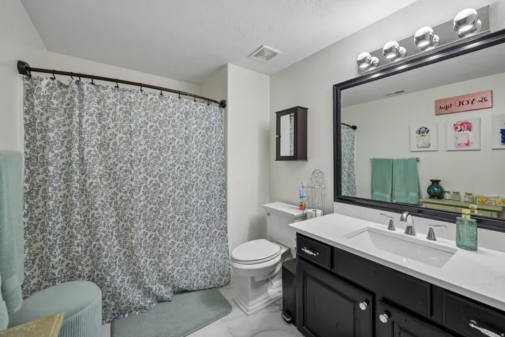 White vanity with a rectangular undermount sink, a chrome two-handle faucet, and black cabinetry