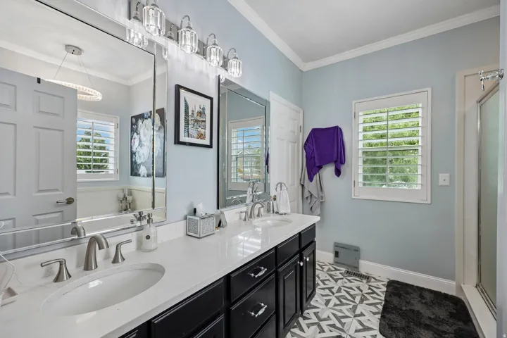 Dual vanity with undermount sinks and brushed nickel fixtures, white countertop, dark wood-finish cabinetry, and patterned tile flooring