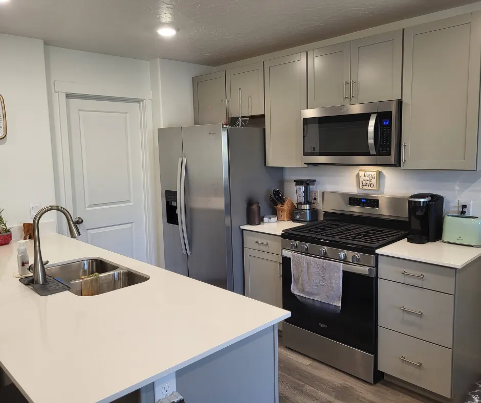 Kitchen featuring light gray cabinetry, stainless steel appliances, a gas range, and white countertops