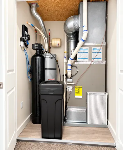 Utility closet featuring a water heater, water softener system, and forced-air unit