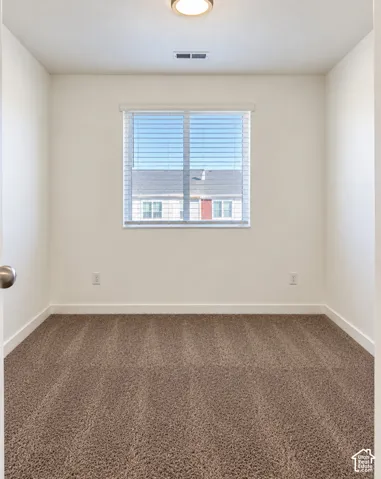 Neutral-toned carpet flooring, white walls, and a window with horizontal blinds