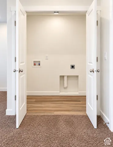 Laundry area with wood-finish flooring, white trim, and dual panel doors
