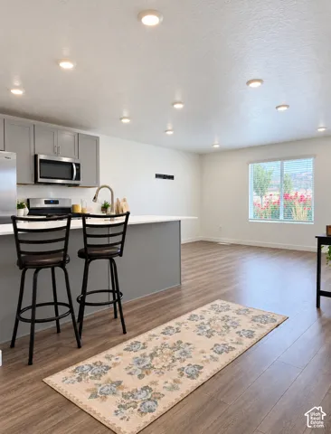 Kitchen with gray cabinetry, white countertops, stainless steel appliances, and a central island