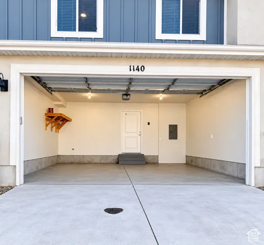 Spacious two-car garage featuring a finished interior with neutral wall finishes, concrete flooring, overhead track lighting, and an interior service door
