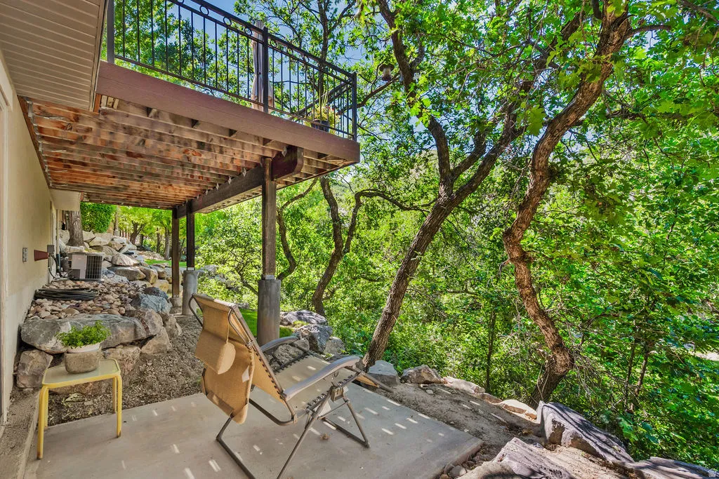 Outdoor patio with a concrete surface, covered by an upper deck featuring a black metal railing