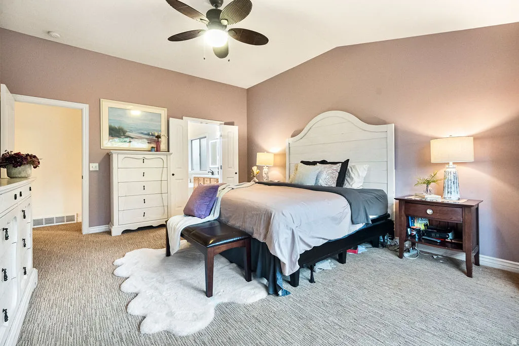 Vaulted ceiling with an attached ceiling fan, wall-to-wall carpeting, and a built-in closet with double doors
