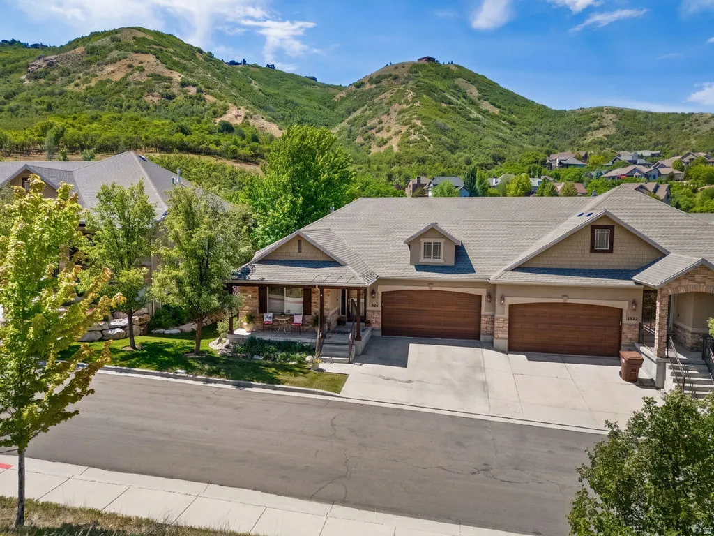 Property exterior featuring a stone and siding facade, a covered front porch, a two-car garage with wood-finish doors, and a paved driveway