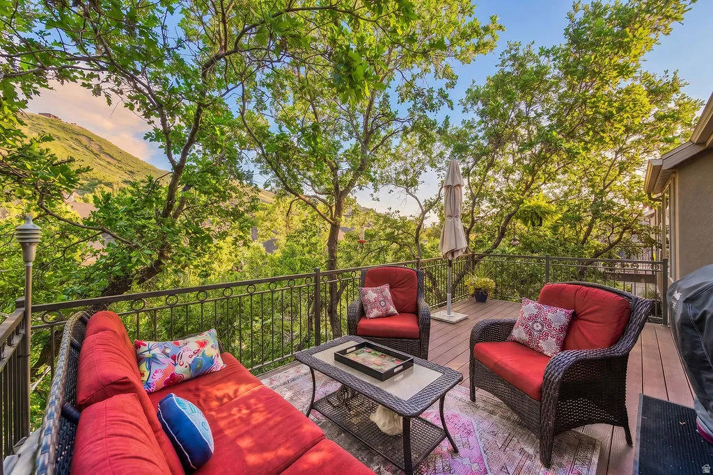 Expansive outdoor deck featuring wood-finish flooring, wrought iron railing, and a mountainous backdrop