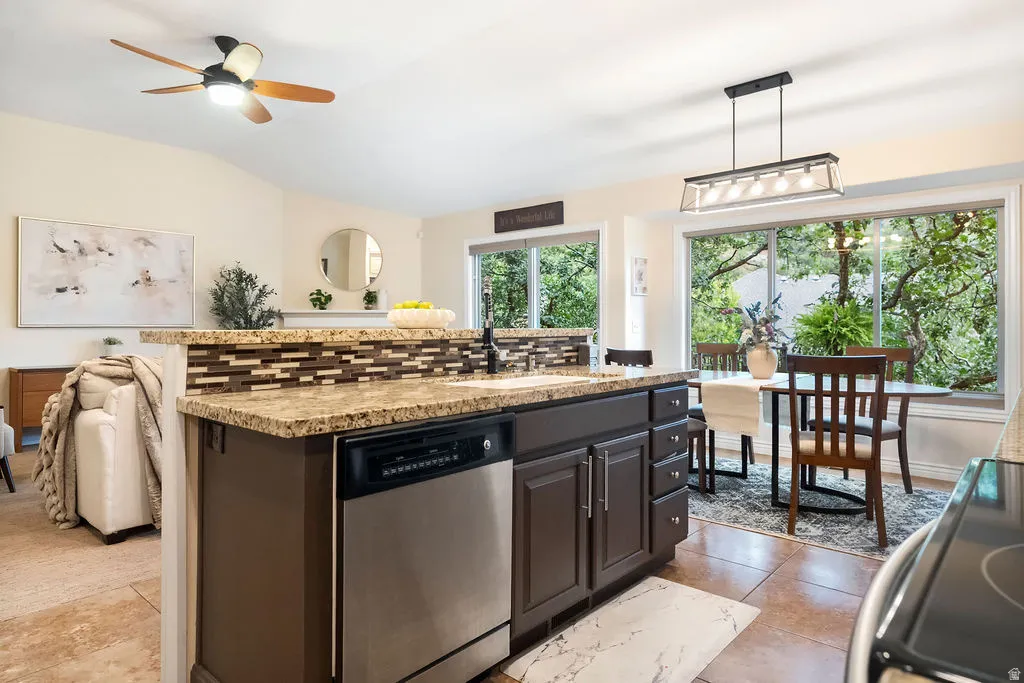 Kitchen island with granite countertops, integrated stainless steel dishwasher, and a mosaic tile backsplash