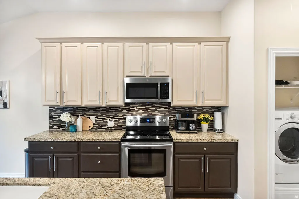 Kitchen featuring two-tone cabinetry, stainless steel appliances, granite-style countertops, and a mosaic tile backsplash