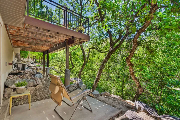 Outdoor patio with a concrete surface, covered by an upper deck featuring a black metal railing