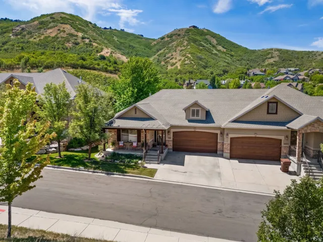 Property exterior featuring a stone and siding facade, a covered front porch, a two-car garage with wood-finish doors, and a paved driveway
