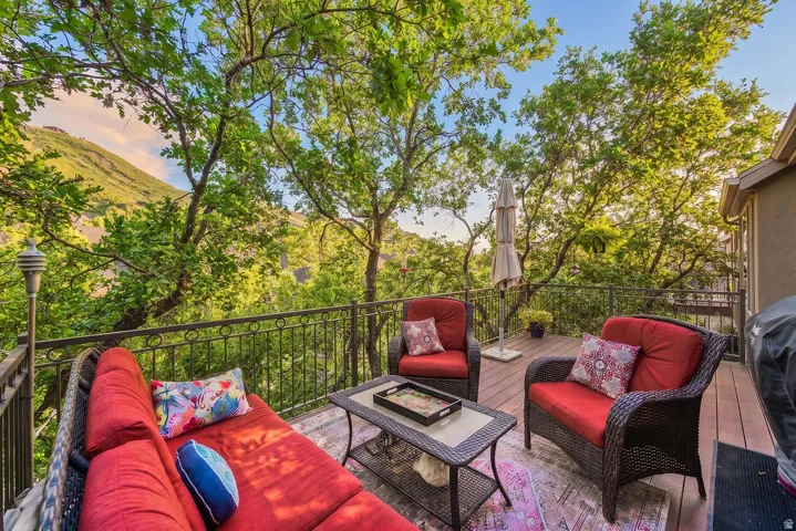 Expansive outdoor deck featuring wood-finish flooring, wrought iron railing, and a mountainous backdrop