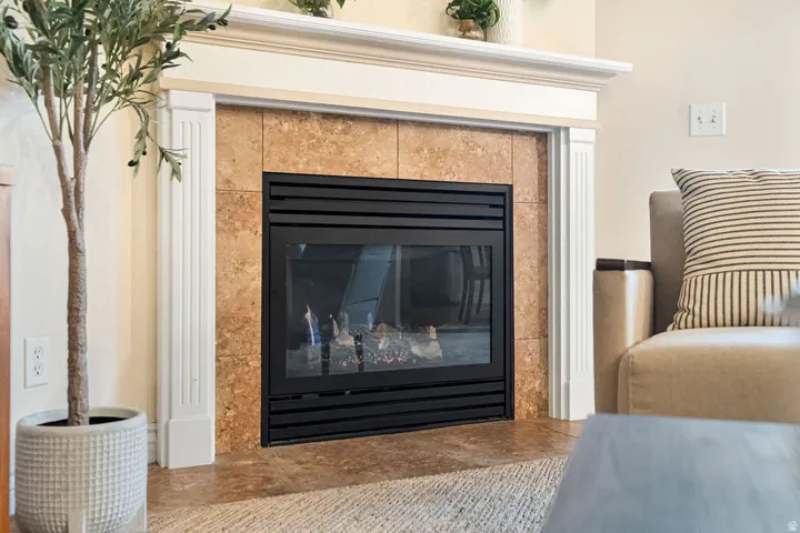 Elegant living room showcasing a wood-burning fireplace with black metal surround and cork-finish surround panels, framed by white trim molding
