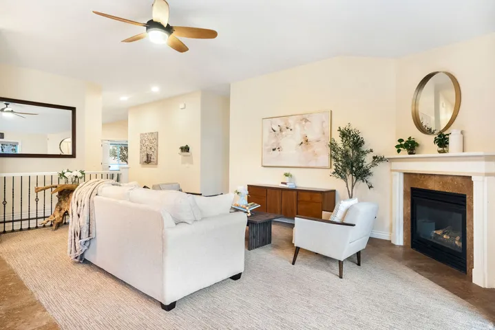 Living space with a ceiling fan, recessed lighting, and a fireplace featuring a stone surround and a white mantel