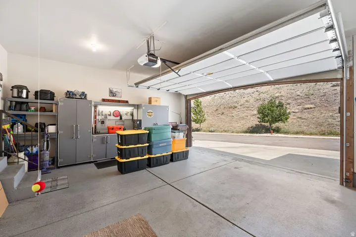 Spacious garage with automatic overhead door, concrete flooring, built-in storage cabinets, and wall-mounted shelving