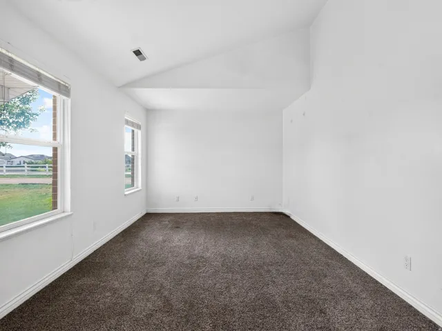 Vaulted ceiling, two windows, wall-to-wall carpeting, and white walls