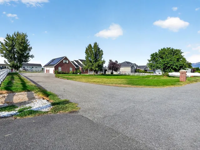 Paved driveway leading to a brick residence with solar panels and an attached two-car garage