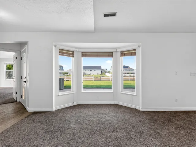 Bay windows, carpeted flooring, wood-finish flooring, white walls, and white trim
