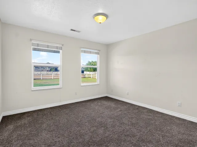Neutral wall color, two windows, textured ceiling, flush mount ceiling light, and dark-toned carpet flooring