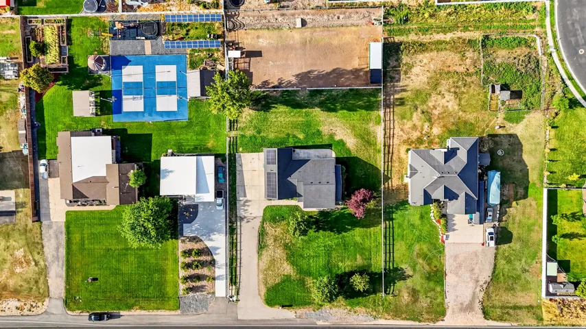 Expansive property featuring multiple structures, manicured lawns, paved driveways, and a distinct sports court