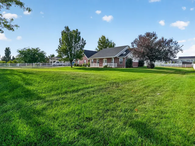 Expansive green lawn with mature trees and a white fence