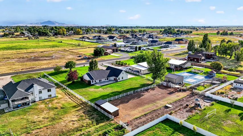 Expansive lot featuring a tennis court, a detached shed, a white picket fence, and a mountain backdrop