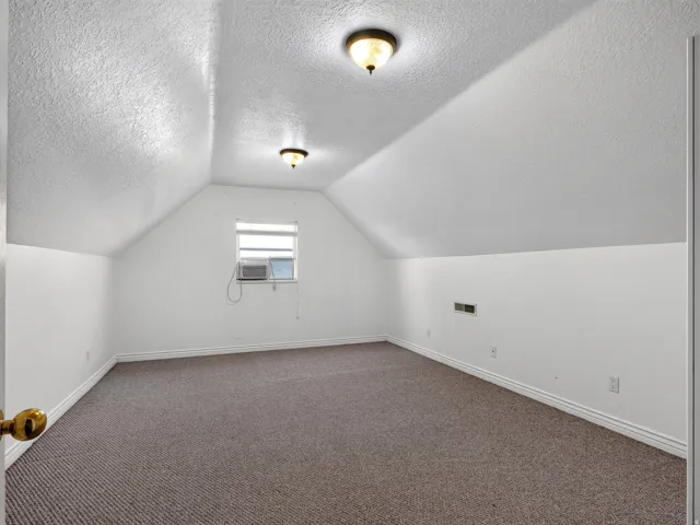 Carpeted room featuring a window and two ceiling-mounted light fixtures