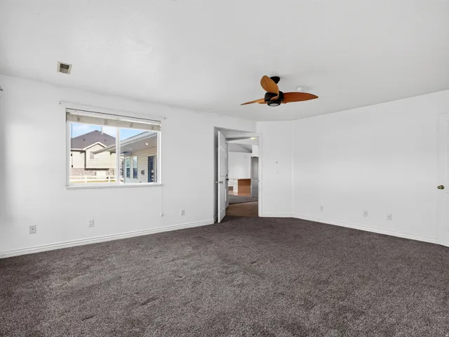 Carpeted interior with a ceiling fan, a window, and a white paneled door
