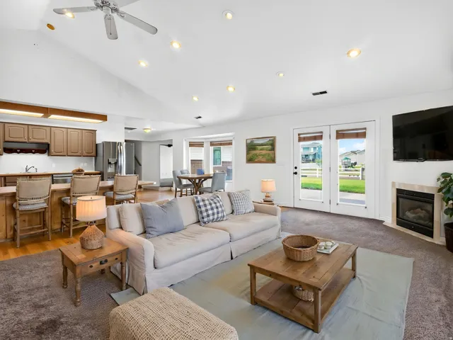Vaulted ceiling with recessed lighting and ceiling fan, two sets of French doors, built-in fireplace, and a breakfast bar with wood-finish cabinetry