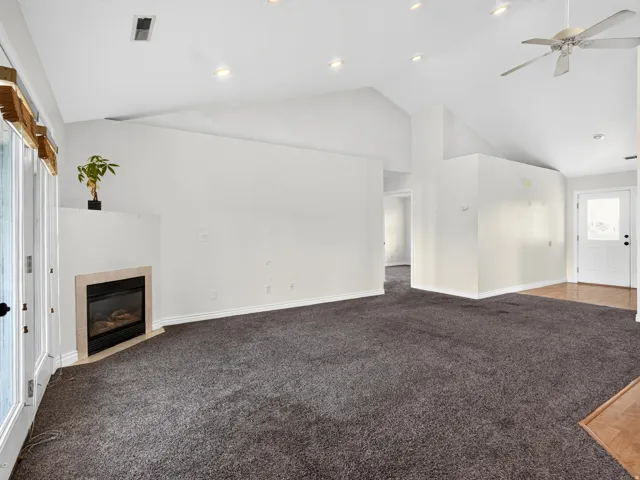 Vaulted ceilings, recessed lighting, and a fireplace with a stone surround
