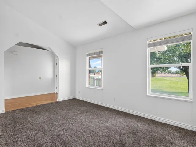 Carpeted flooring, vaulted ceiling, and two windows providing natural light