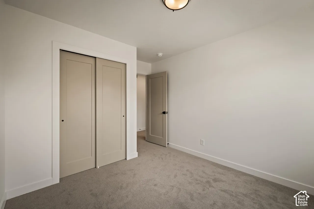Neutral wall color, carpet flooring, flush mount ceiling light, sliding closet doors, and single panel interior door