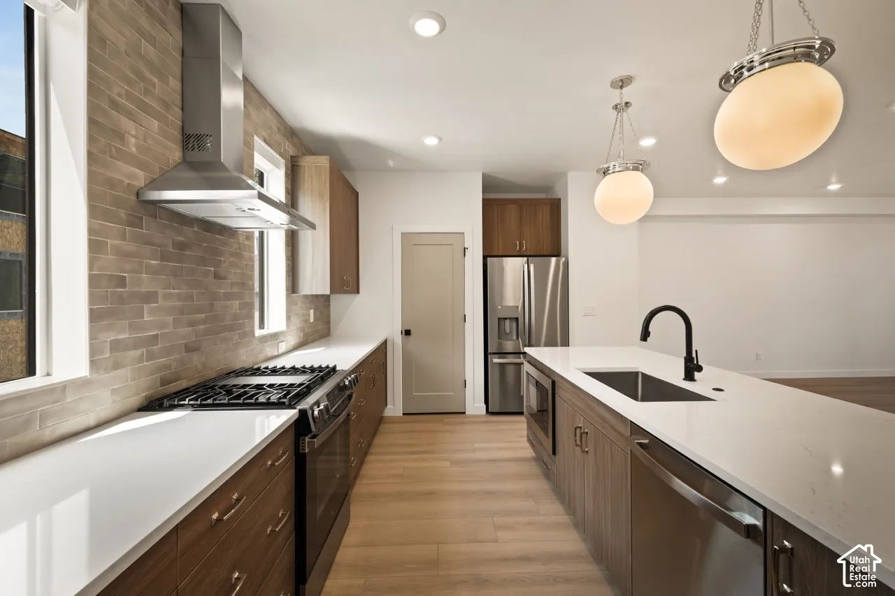 Modern kitchen featuring an expansive island with a matte black faucet, stainless steel appliances, wood-finish cabinetry, and a brick-patterned backsplash