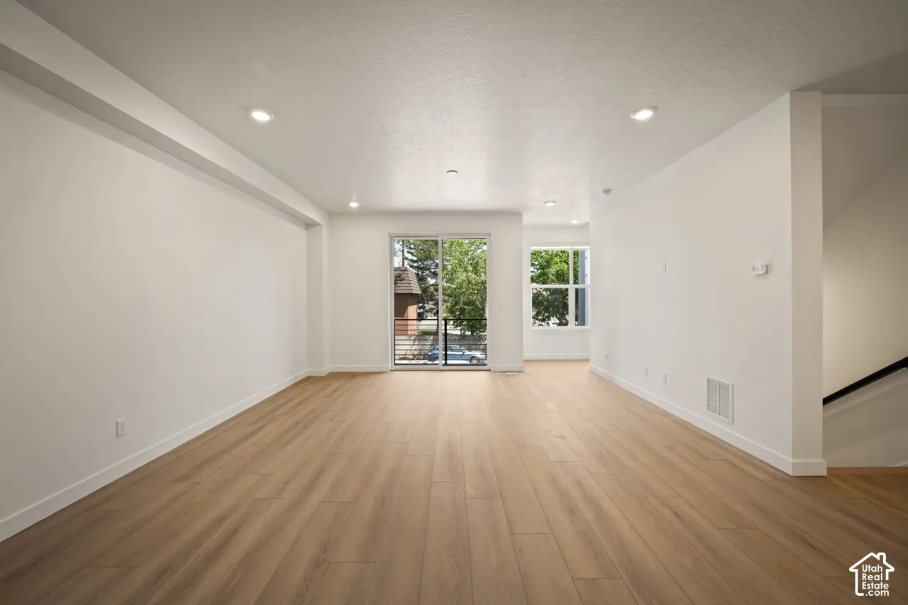 Recessed lighting, wood-finish flooring, white walls, large sliding glass door, and a window