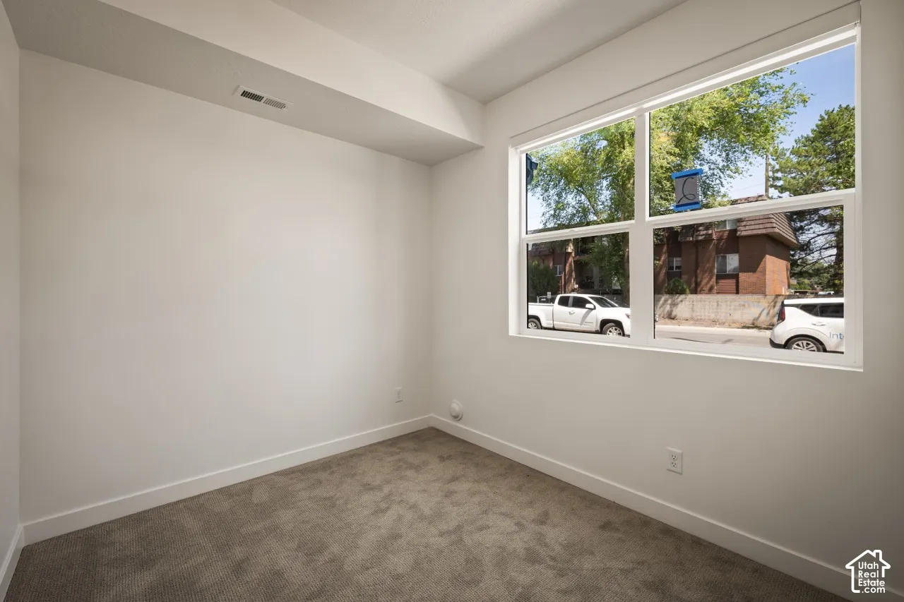 Large picture window, white trim, textured carpet flooring, white walls, recessed ceiling fixture