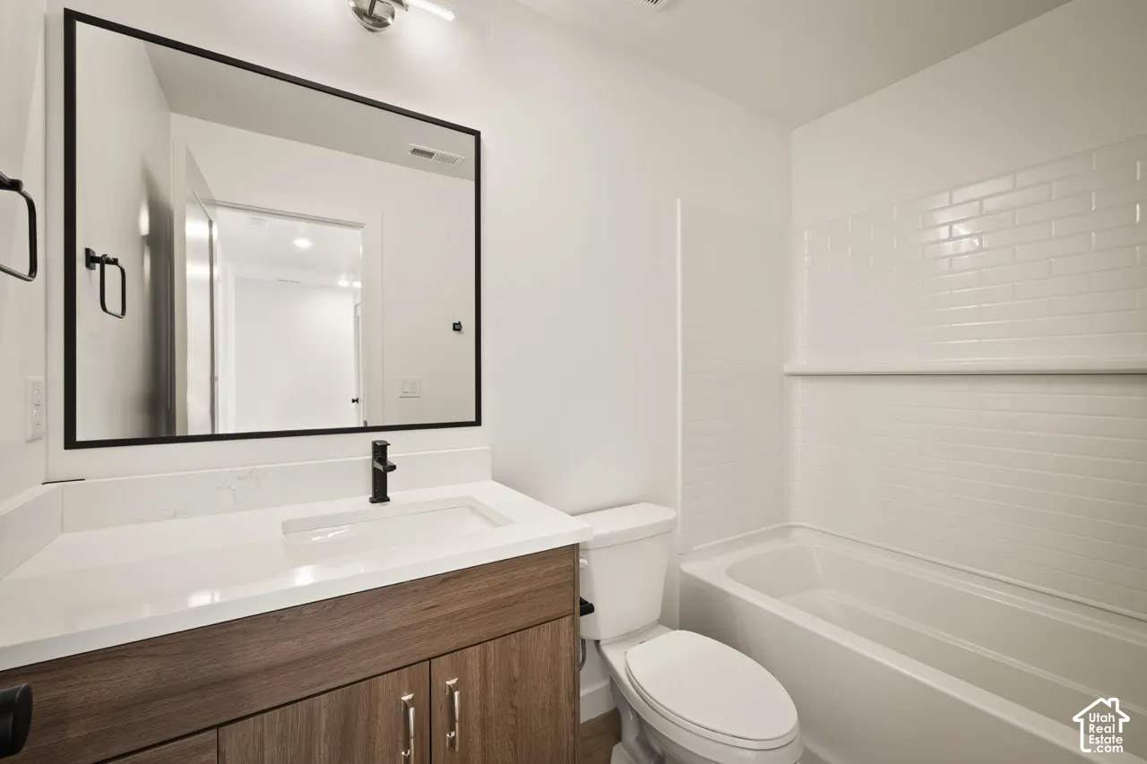 Bathroom with wood-finish vanity, white countertop, and integrated sink