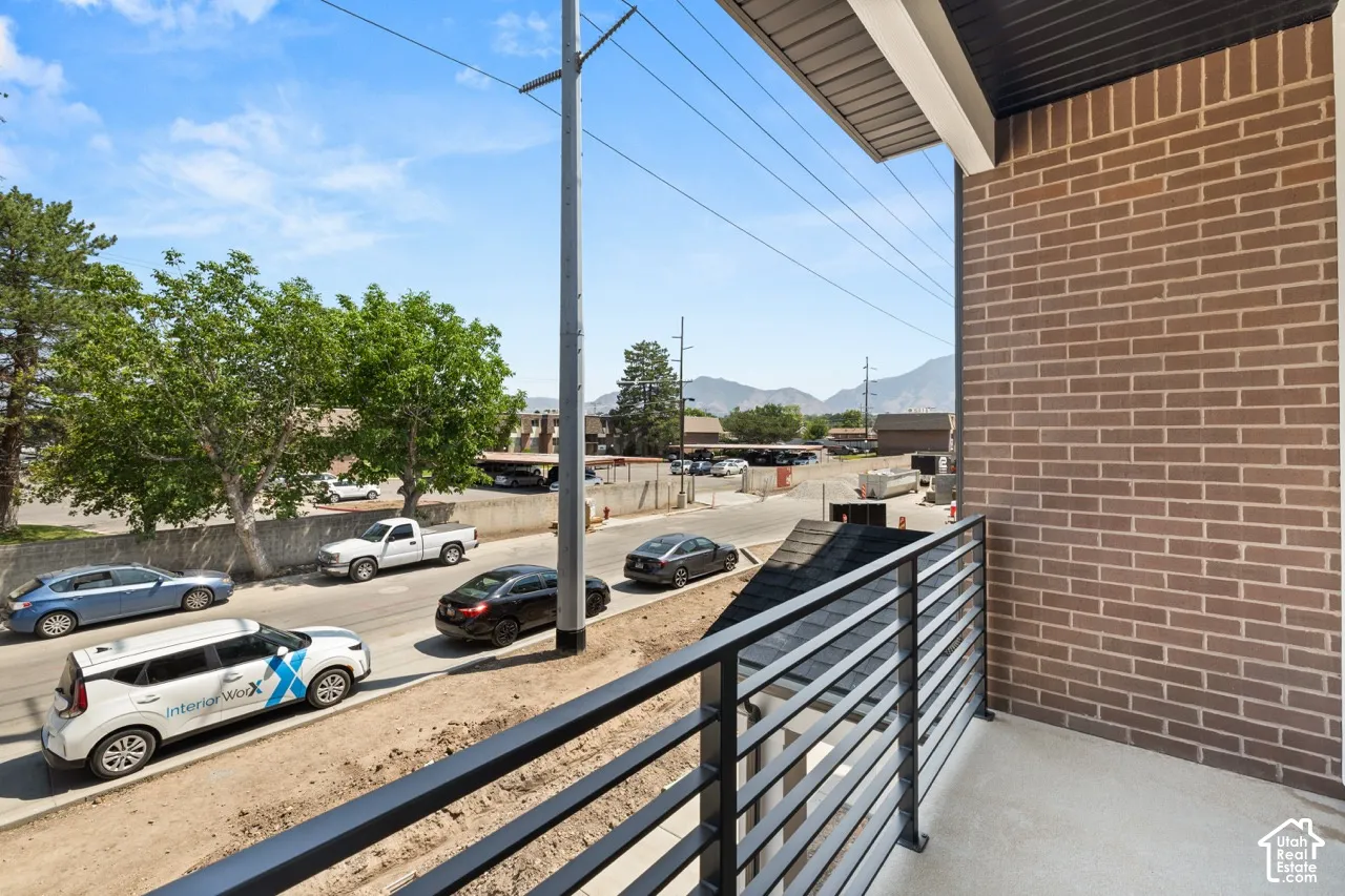 Private balcony with a metal horizontal slat railing and a brick exterior wall