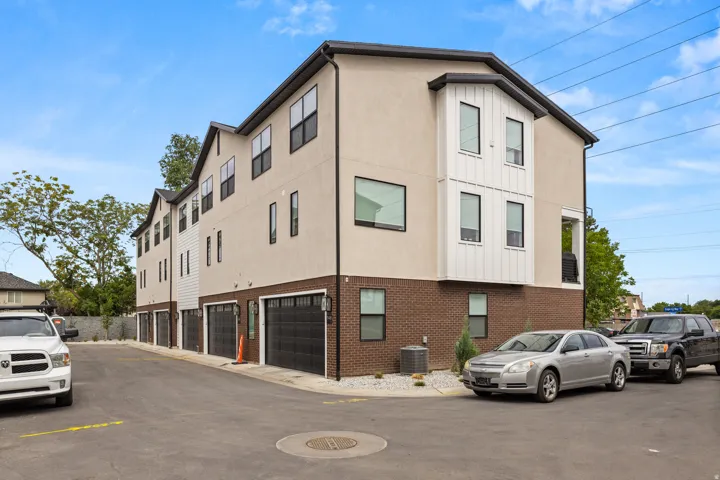 Contemporary multi-story exterior with a mix of stucco and brick siding, multiple black garage doors, and dark-framed windows